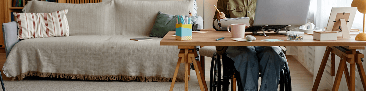 Photo qui montre une femme en situation de handicap dans un fauteuil roulant en train de travailler à distance